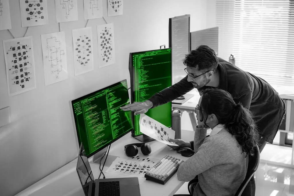 Two engineers reviewing a generated migration plan on screen, architecture diagrams pinned on the wall
